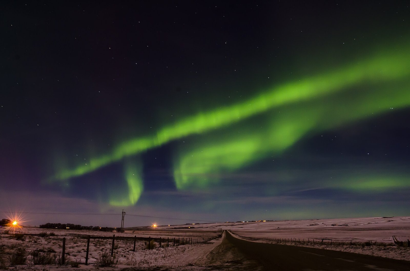 Green aurora borealis rippling across the night sky over snow