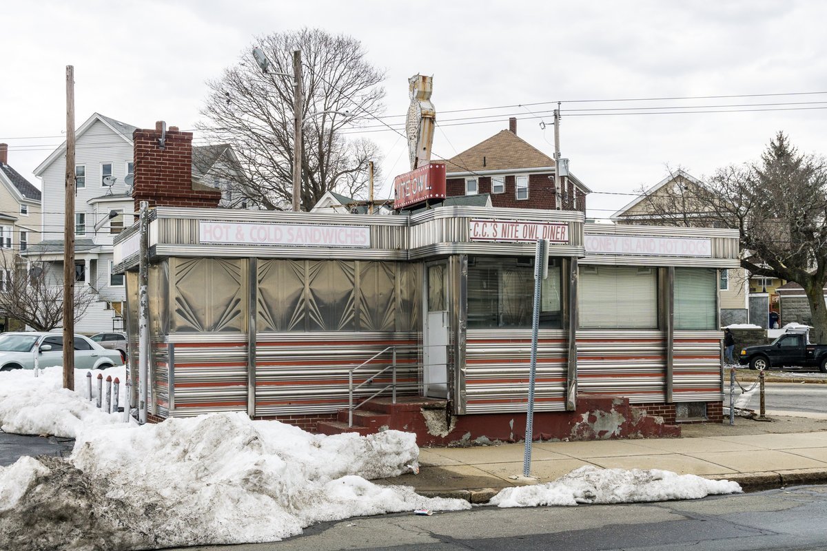 A classic American diner counter with red stools, a burger and milkshake on the counter